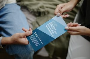 Young Adult Woman Handing Social Worker Brochure to Young Teenager