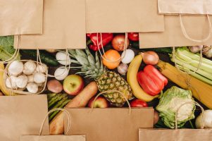 top view of shopping bags covering vegetables and fruits on wooden table
