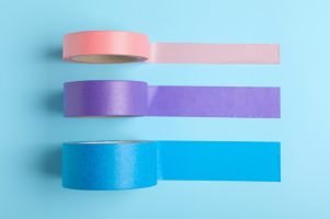 Many rolls of adhesive tape on light blue background, flat lay