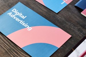 Two brochures with digital advertising brief course surrounded by documents